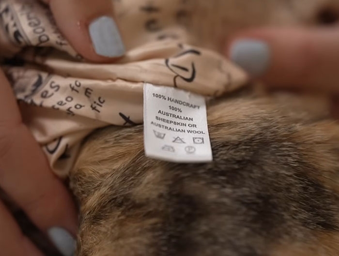 Close-up of a clothing label claiming Australian wool on a vest, revealing controversy over cat fur use in fashion products. Close-up of a clothing label claiming Australian wool on a vest, revealing controversy over cat fur use in fashion products.