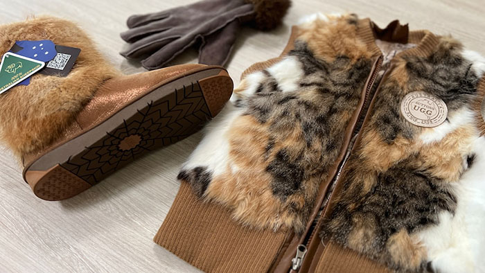 Fur vest and boots with fur trim laid out on table, highlighting controversy over cat fur use in fashion products. Fur vest and boots with fur trim laid out on table, highlighting controversy over cat fur use in fashion products.