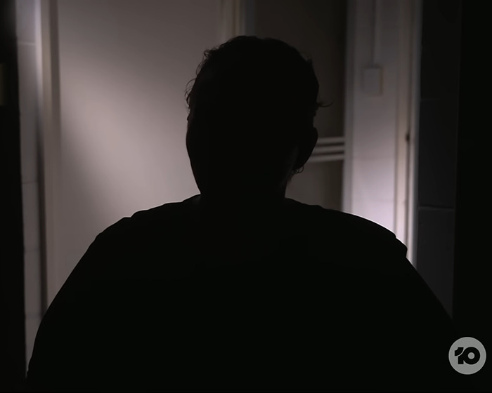 Silhouetted teen mourner in a dimly lit room, reflecting devastation during a funeral hearse procession.