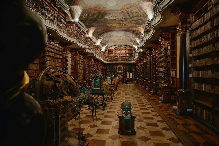 Ornate historic library interior with high shelves, decorative ceiling, and antique globes showcasing stunning bookstores and libraries.