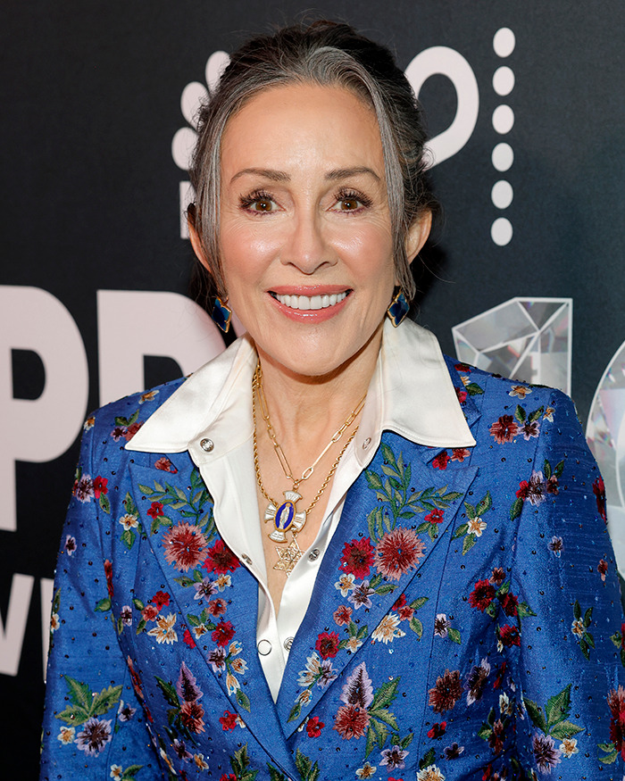 Woman wearing a blue floral blazer and white shirt smiling at event, representing celebrities with body abnormalities