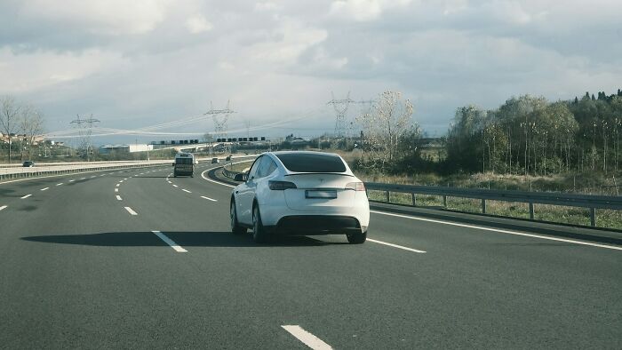 White car driving on an empty highway under cloudy skies, representing creepy and scary moments from truck drivers’ lives.