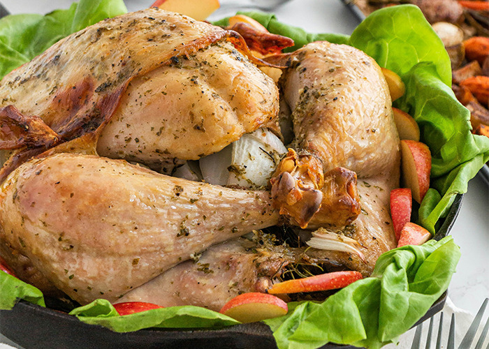 Roasted chicken drumsticks with herbs and vegetables on a bed of fresh lettuce, promoting healthy eating habits.