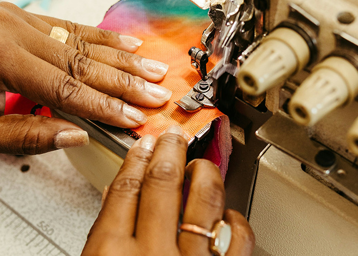 Hands guiding colorful fabric through a sewing machine, illustrating habits that may improve your quality of life.