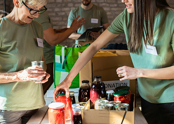 Volunteers sorting canned and bottled goods in donation boxes, demonstrating habits that improve quality of life.