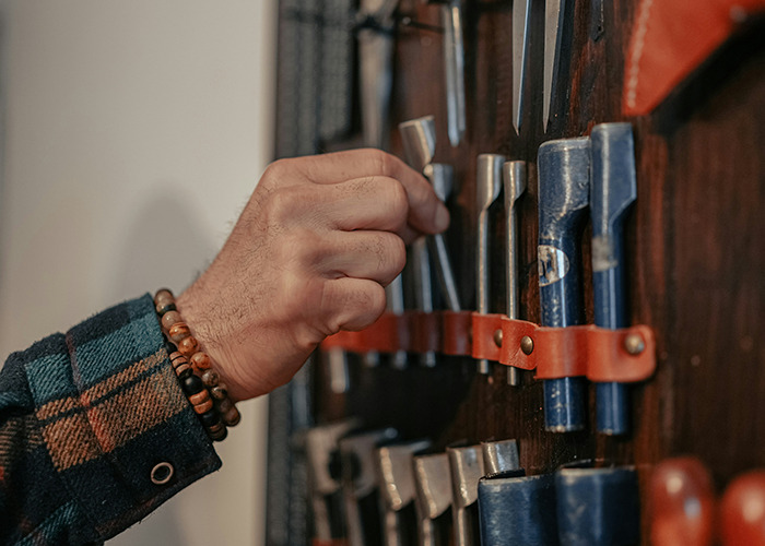 Hand selecting chisels from a leather tool holder, demonstrating habits that may improve your quality of life.