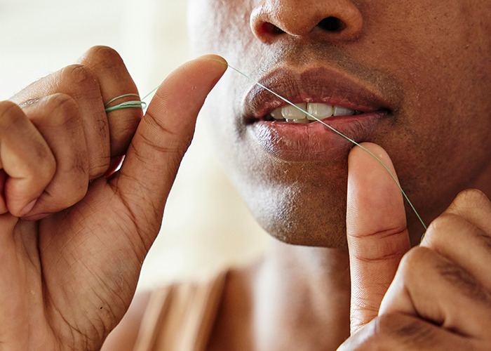 Person flossing teeth closeup, demonstrating one of the habits to improve quality of life and oral health care.