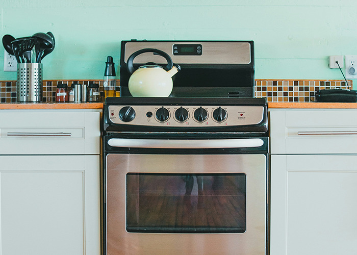 Modern kitchen stove with a kettle on top, representing habits that may improve your quality of life in a home setting.