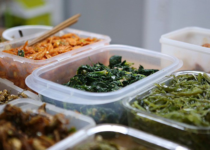 Plastic containers filled with various cooked vegetables and greens, illustrating healthy habits to improve quality of life.