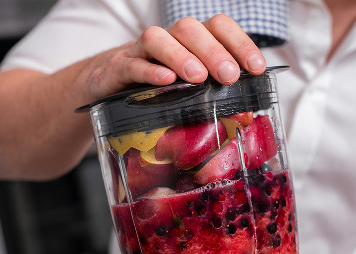 Person holding a blender filled with fresh fruit, illustrating healthy habits to improve quality of life.