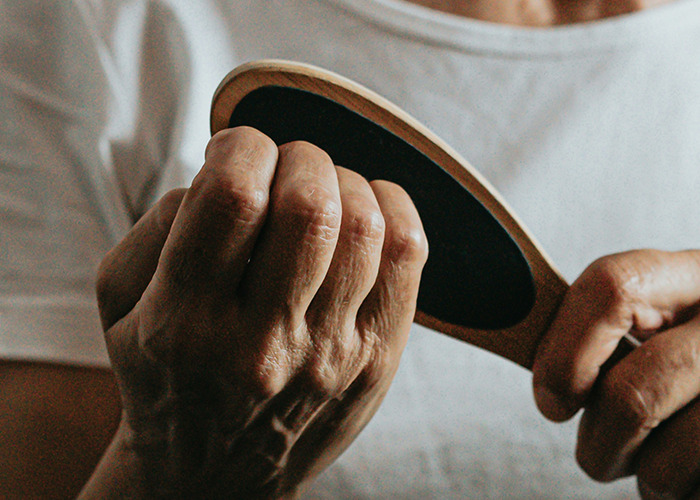 Close-up of a person holding a wooden paddle brush, illustrating habits that may improve your quality of life.
