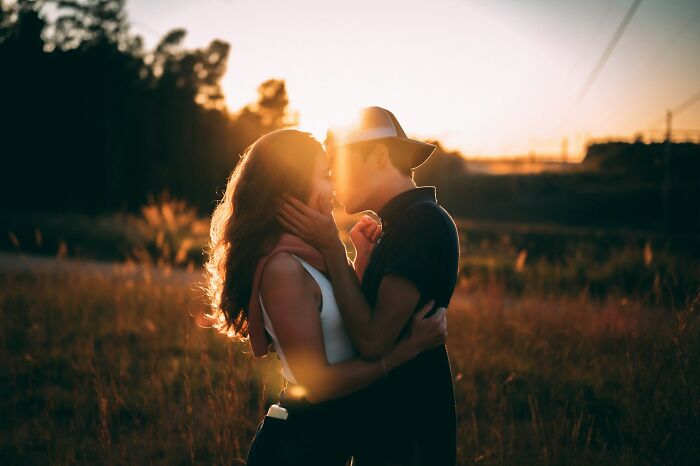 Couple embracing at sunset in a field, illustrating challenges and emotions in modern dating experiences.