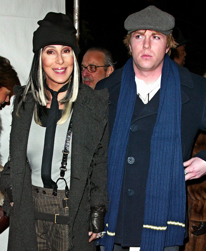 Cher smiling in a black hat and coat with her son, capturing a moment amid his near-fatal overdose struggles.