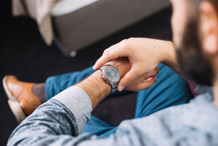 Man checking his watch while sitting, representing a man wanting to save money on dinner with coupon. Man checking his watch while sitting, representing a man wanting to save money on dinner with coupon.