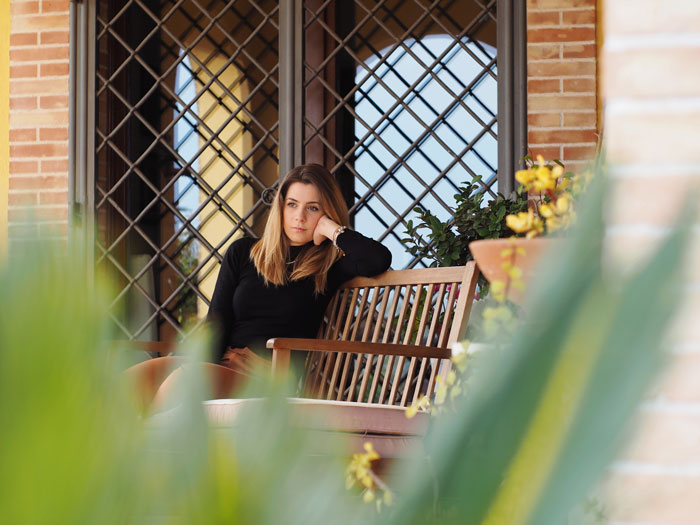 Woman sitting on wooden bench outdoors looking thoughtful with plants in foreground, representing coupon dinner debate. Woman sitting on wooden bench outdoors looking thoughtful with plants in foreground, representing coupon dinner debate.