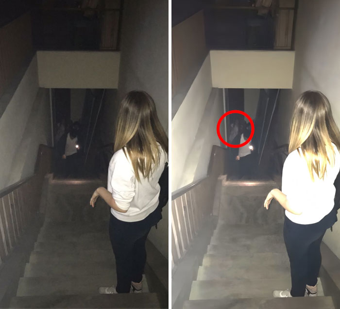 A girl standing on stairs looking at a ghostly figure holding a flashlight in a dark hallway during ghost encounters.