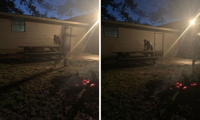 Dimly lit backyard with glowing embers, picnic table, and a shadowy figure near a house at night, evoking ghost encounters.