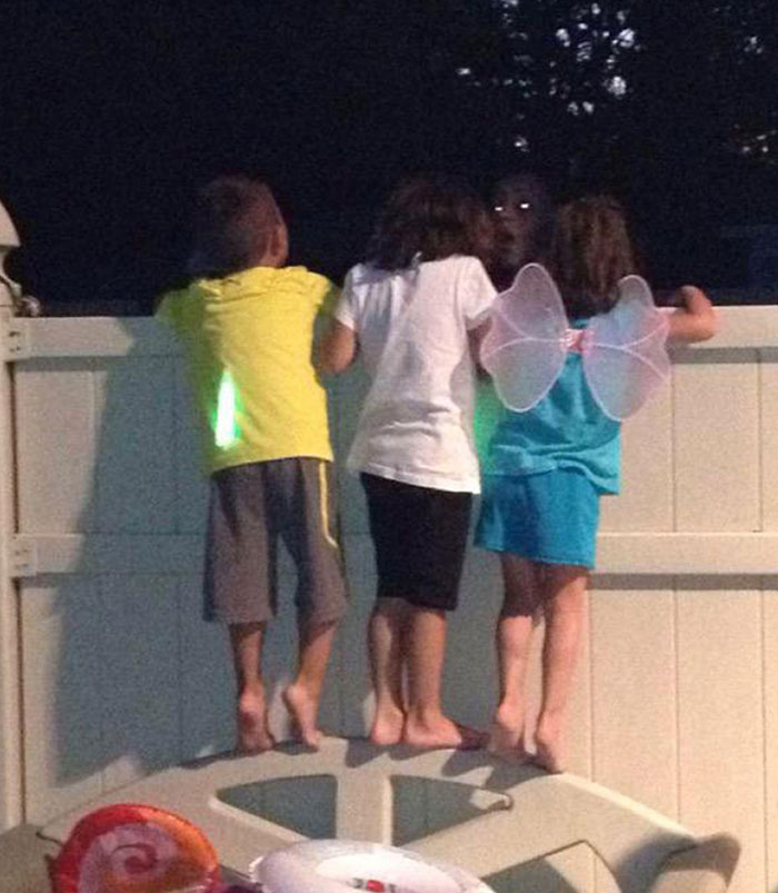 Three children standing on a plastic play structure at night, appearing to witness a chilling ghost encounter.
