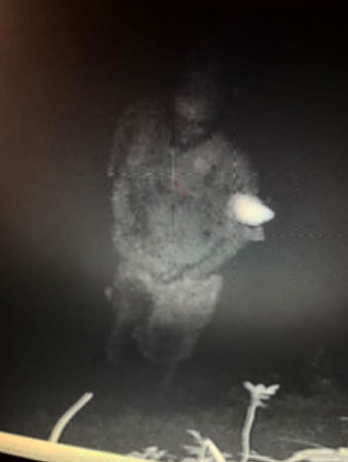 Faint ghostly figure captured at night in a dark outdoor setting, evoking chilling ghost encounter vibes.