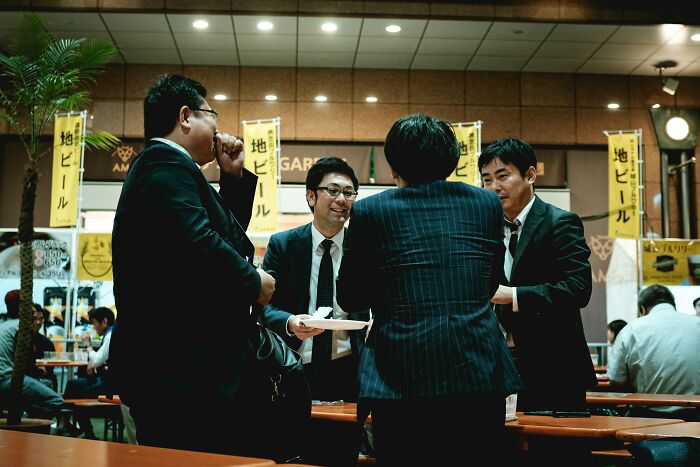 Group of men in suits socializing in a Japanese bar, illustrating challenges of being big in Japan in real life.