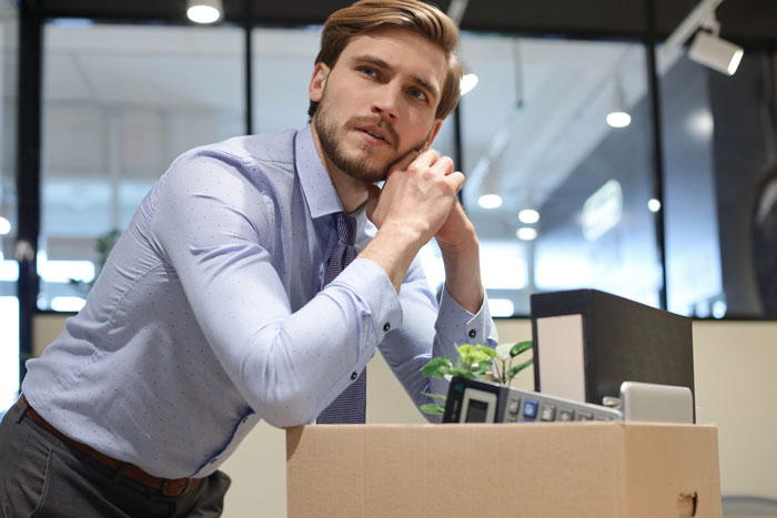 A worried client leans on a desk with a box of office items, reflecting panic after designer stops follow-ups on approvals. A worried client leans on a desk with a box of office items, reflecting panic after designer stops follow-ups on approvals.