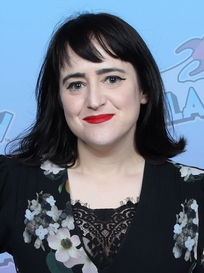 Woman with black hair and red lipstick smiling at an event featuring former Hollywood stars who left the spotlight for normal careers.