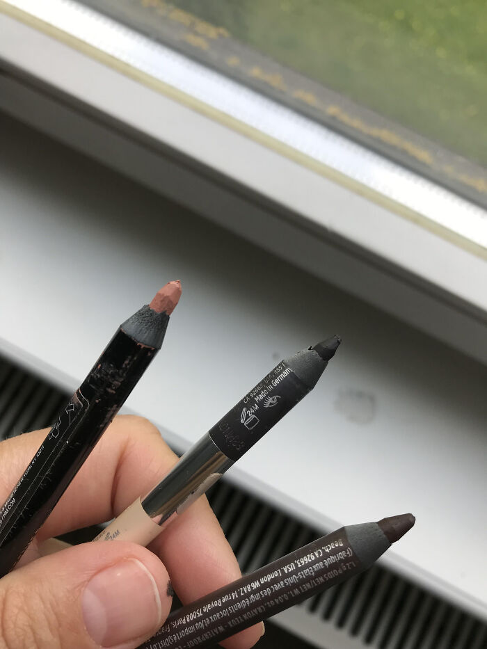 Hand holding three makeup pencils near a window, illustrating women’s experiences with dismissive doctors.
