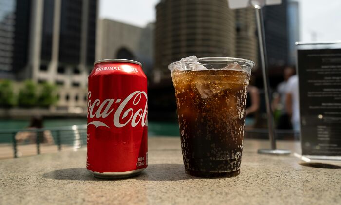 Can of soda and iced drink on a table, illustrating non-Americans habits viewed like breaking spaghetti by Italians.