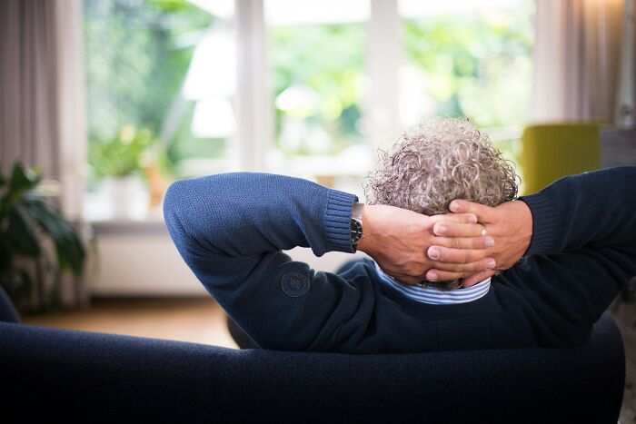 Person with curly hair relaxing on a couch, reflecting on casual habits that may be damaging in the long run.
