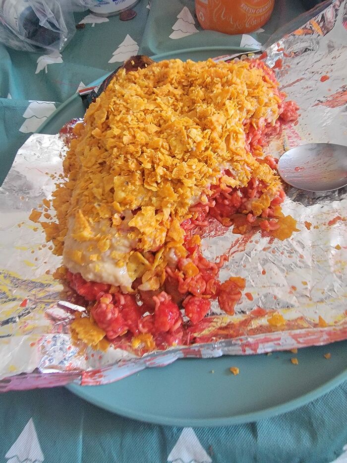 Unappetizing layered food covered with crushed chips on foil, illustrating gross foods that might make you lose your appetite.