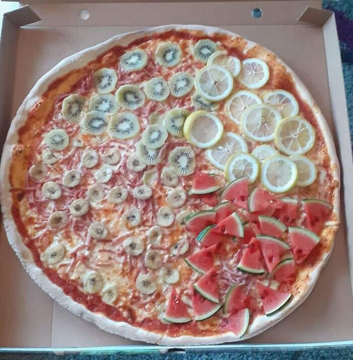 Pizza topped with unusual fruits including kiwi, banana, lemon, and watermelon, featured in gross foods collection.