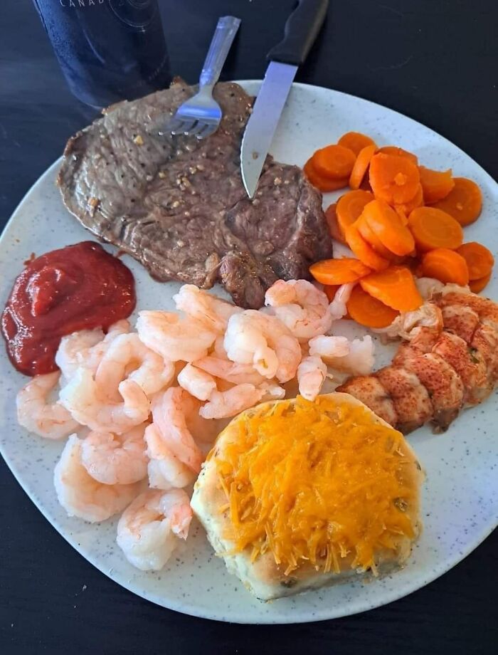 Plate with steak, shrimp, cooked carrots, cheesy biscuit, and ketchup, illustrating gross foods that lose appetite.