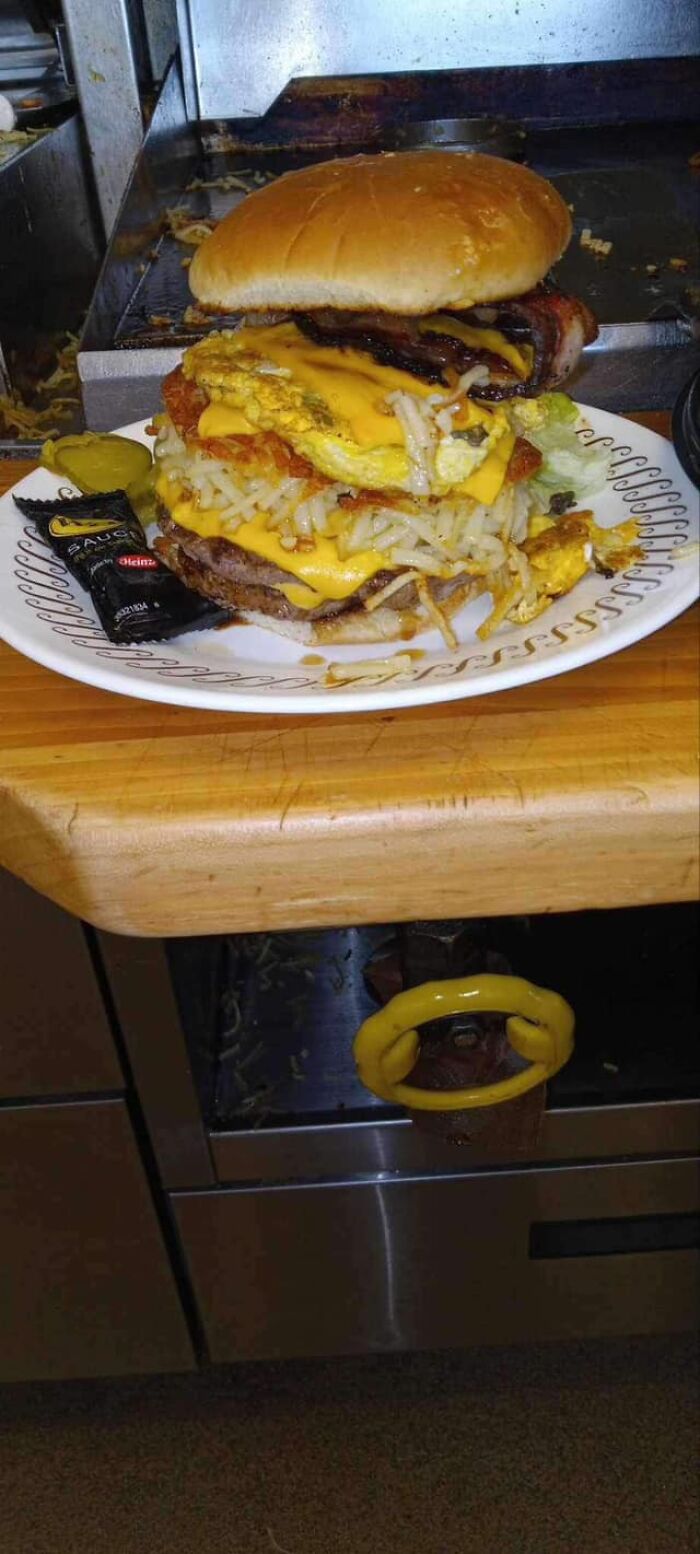 Huge greasy cheeseburger with egg, bacon, and hash browns piled high representing gross foods that might lose your appetite.
