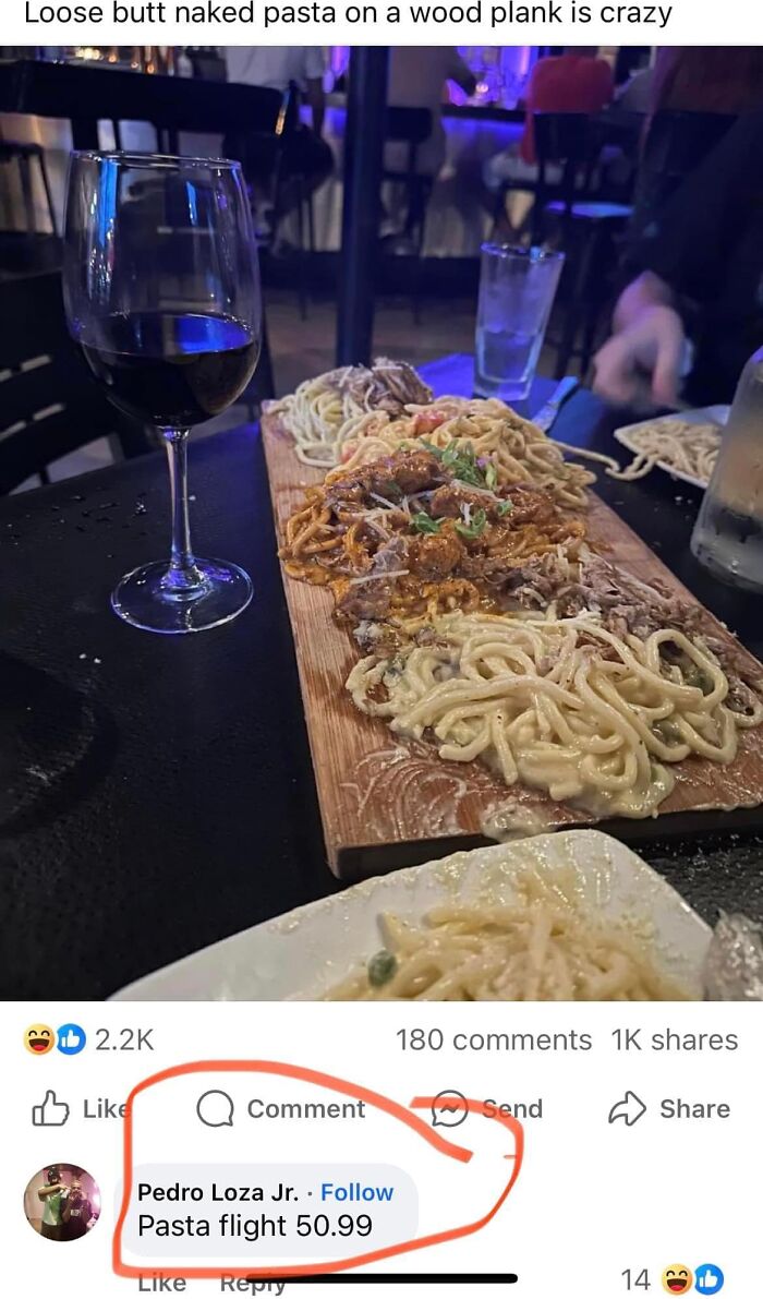 Pasta flight served on a wooden plank with multiple sauces, accompanied by a glass of red wine at a restaurant table.