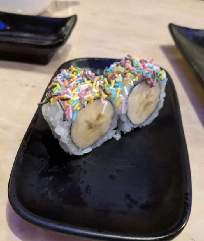 Banana sushi rolls topped with colorful sprinkles on a black plate, an example of gross foods affecting appetite.