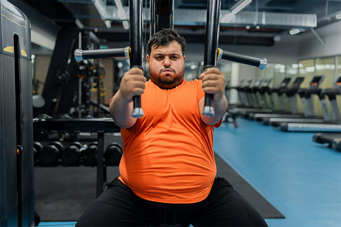 Man focused on workout in gym, illustrating what cool kids who peaked in high school are doing now in adulthood.