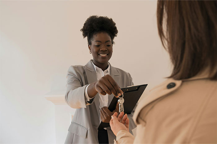 Young professional handing keys to client, illustrating what the cool kids who peaked in high school are doing now.