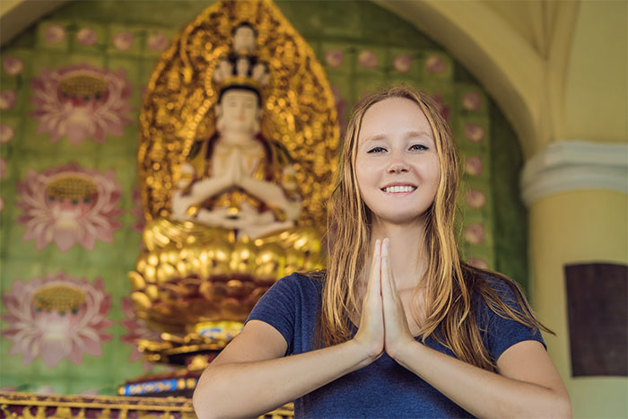 Young woman in blue shirt with hands in prayer pose, reflecting on what cool kids who peaked in high school are doing now