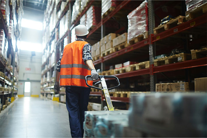 Worker in safety vest and helmet moving pallets in a warehouse illustrating what cool kids who peaked in high school are doing now