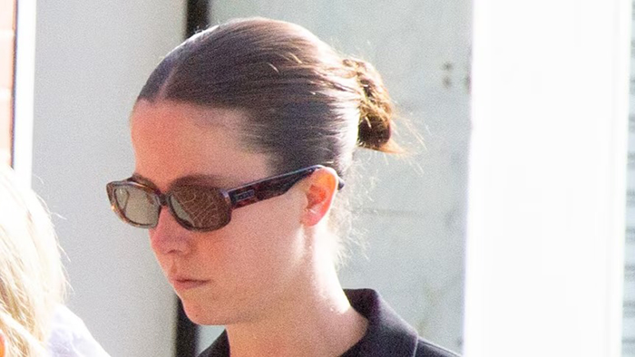 Woman wearing sunglasses and black top, walking outside, related to case of setting male friend on fire over misogynistic comment.