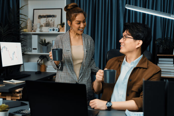 Two colleagues in an office holding mugs, illustrating ways to call out corporate pals’ lies from polite to rude.