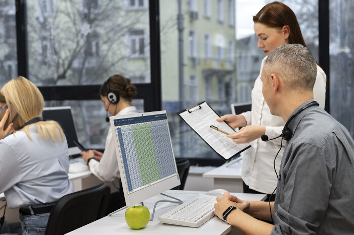 Corporate employees working in an office, discussing data on computers, illustrating ways to call out corporate pals’ lies.