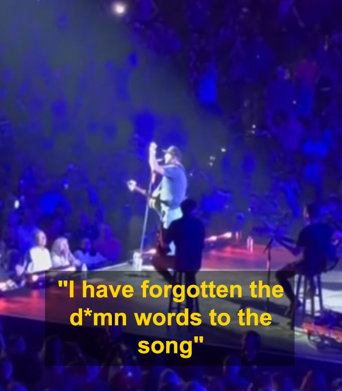 Country star on stage in blue lighting abruptly stops singing mid-concert after forgetting all the words.