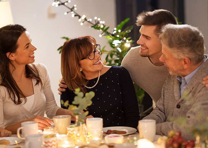 Woman smiling with family around a dinner table, discussing MIL landscaping her garden without permission after vacation.