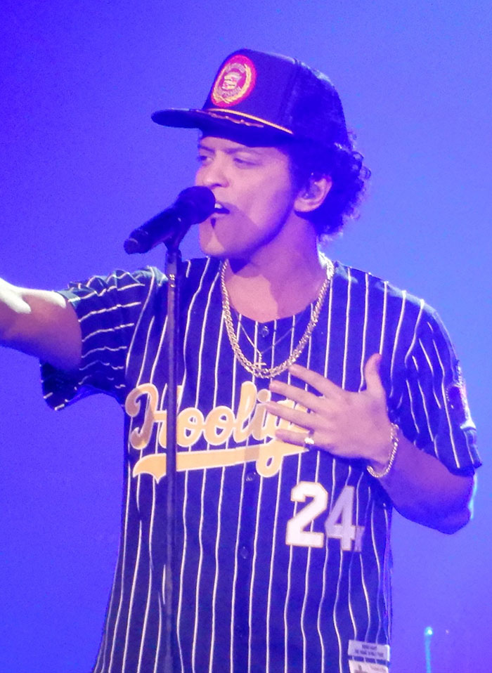 Singer performing on stage with microphone wearing a striped jersey and cap, related to celebrity rumors.