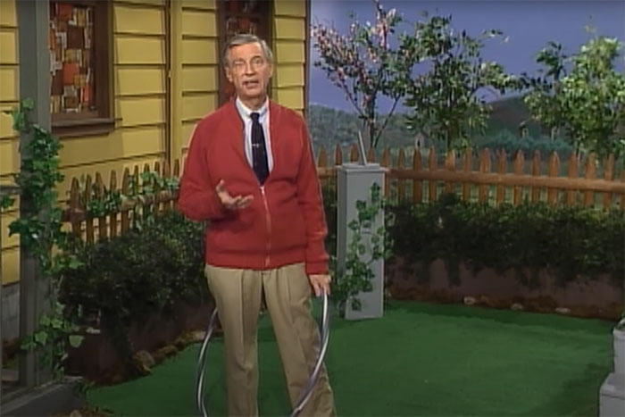 Man in a red cardigan standing outside on green grass, illustrating wildest rumors going around about celebrities.