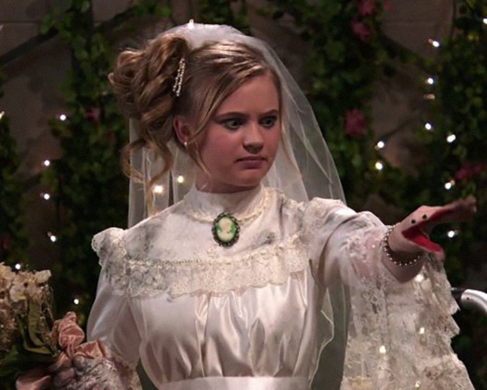 Young woman in vintage wedding dress with veil and glove puppet, highlighting child star's unrecognizable transformation and Disney concerns.