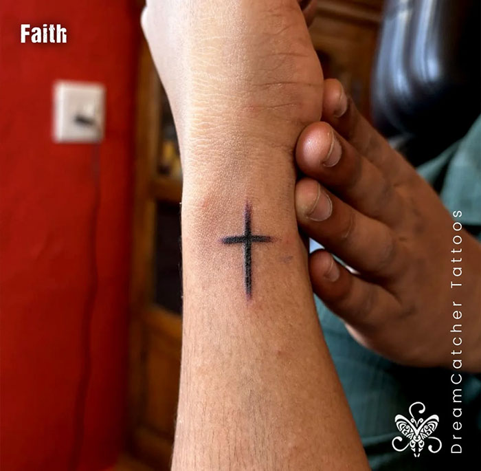 Minimalist black cross tattoo on wrist showcasing faith in a visual guide to cross tattoos for men.