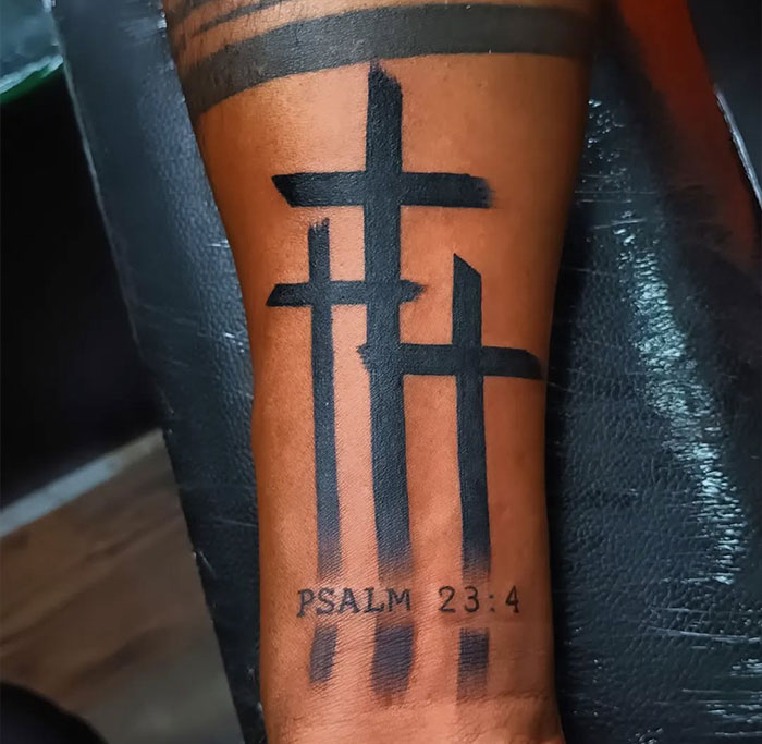 Three black cross tattoos with Psalm 23:4 text on a man's forearm, showcasing a bold cross tattoo design for men.