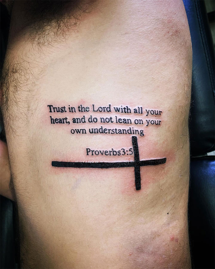 Tattoo of a cross with Proverbs 3:5 quote on a man's side, showcasing a bold cross tattoo design for men.